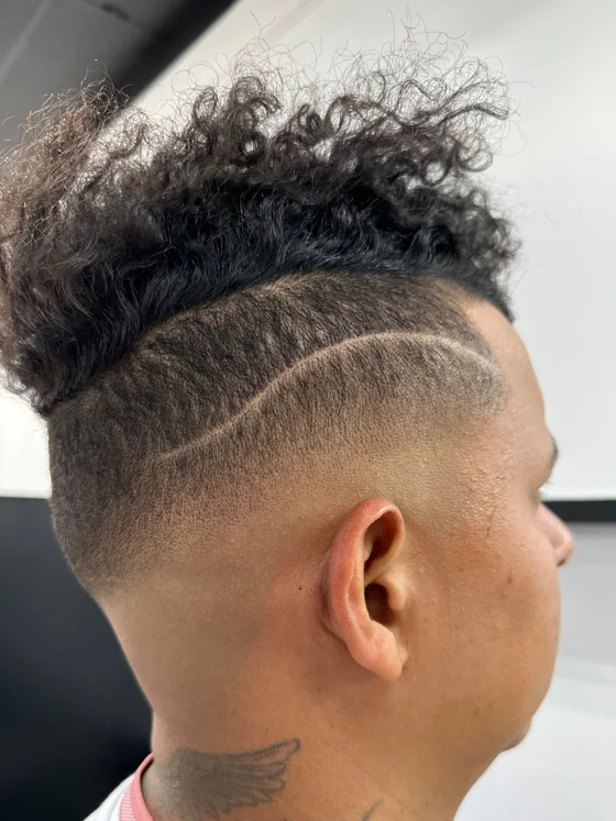 Curly top with burst fade and razor design by barber Daniel Larrosa at Yovany Barbershop #3, North Fort Myers FL